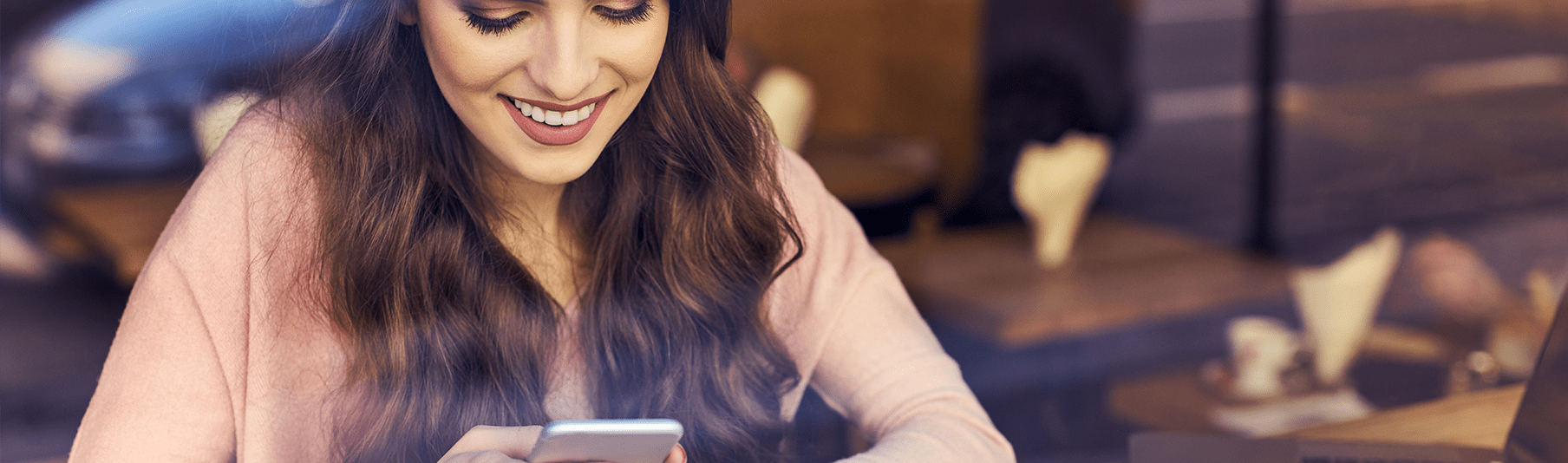 Personal Insurance: A young woman smiling as she looks at something on her phone